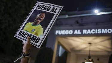 ARCHIVO - En foto del 23 de mayo del 2023, un manifestante sostiene una imagen del futbolista brasileño Vinicius Junior con un mensaje en portugués que se traduce: Pelea contra el racismo durante una manifestación por el racismo contra el jugador. (AP Foto/Tuane Fernandes, Archivo)