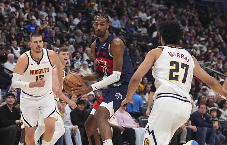 El alero de los Wizards de Washington, Alex Sarr, centro, conduce hacia la canasta entre el pívot de los Nuggets de Denver, Nikola Jokic, izquierda, y el escolta Jamal Murray en la primera mitad de un partido de baloncesto de la NBA, el sábado 15 de marzo de 2025, en Denver. (AP Foto/David Zalubowski)