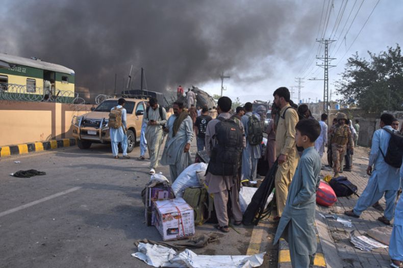Voluntarios buscan víctimas de un vagón de tren volcado, mientras los sobrevivientes esperan a conseguir transporte en el lugar de una explosión en Quetta, Pakistán, el domingo 24 de mayo de 2026. (AP Foto/Arshad Butt)