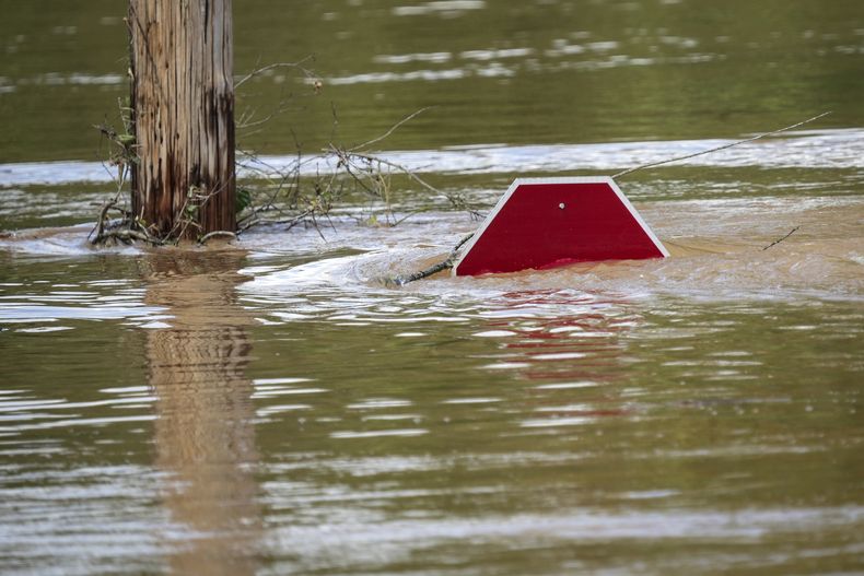 Un letrero de alto apenas asoma por encima del nivel del agua en un estacionamiento inundado por las lluvias torrenciales generadas por el huracán Helene, el sábado 28 de septiembre de 2024, en Morganton, Carolina del Norte. (AP Foto/Kathy Kmonicek)