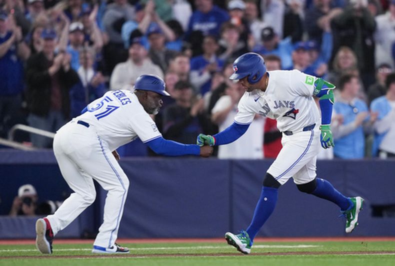El bateador designado de los Azulejos de Toronto, George Springer (4), celebra su jonrón solitario con el entrenador de tercera base, Carlos Febles (51), durante el partido contra los Atléticos en la primera entrada de un encuentro de la Liga Americana de Béisbol en Toronto el domingo 29 de marzo de 2026. (Nathan Denette/The Canadian Press vía AP)