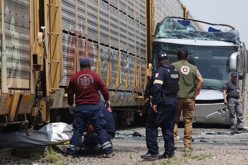 Los rescatistas retiran un cuerpo de la escena de un accidente mortal entre un tren y un autobús de dos pisos en Atlacomulco, México, el lunes 8 de septiembre de 2025. (AP Foto/Ramsés Mercado Valdes)