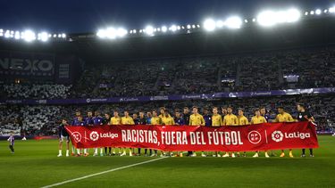 Los jugadores del Barcelona y el Valladolid exhiben una pancarta con la frase Racistas, fuera del fútbol previo al partido de la Liga española, el martes 23 de mayo de 2023, en Valladolid. (AP Foto/Manu Fernández)