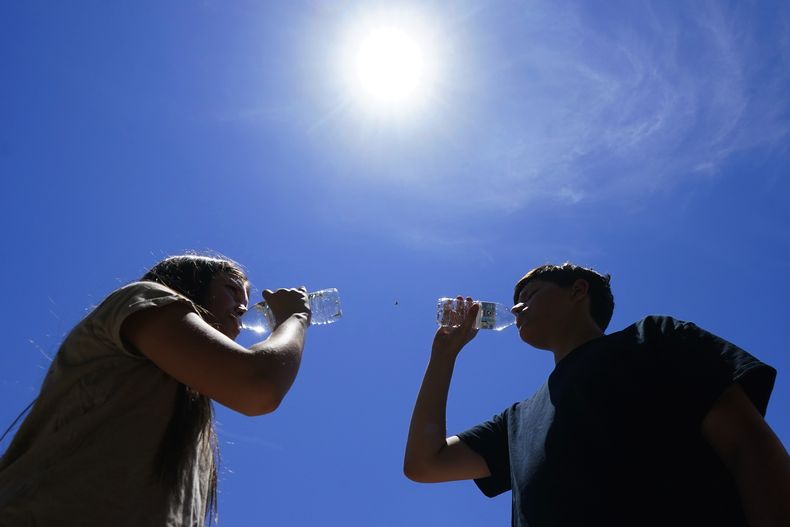 Personas tratan de protegerse del calor en Phoenix el 17 de julio de 2023. (Foto AP /Ross D. Franklin)
