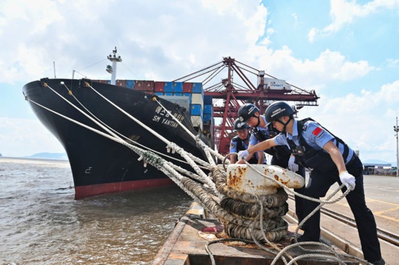 En esta imagen publicada por la agencia de noticias Xinhua, policías comprueban el amarre de una embarcación antes del tifón Dolphin, en el distrito de Beilun en Ningbo City, en la provincia oriental china de Zhejiang, el 7 de agosto de 2026.(Hu Jiajie/Xinhua via AP)