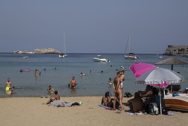 ARCHIVO – Varios turistas disfrutan la playa y el mar de Lindos, en la isla de Rodas, en el mar Egeo, en el sureste de Grecia, el jueves 27 de julio de 2023. (AP Foto/Petros Giannakouris, Archivo)