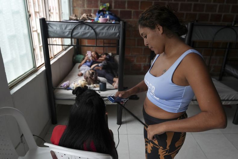 Mariana Ariza, de Venezuela, alisa el cabello de una compatriota en el Refugio para Migrantes Papa Francisco en Palmira, Colombia, el viernes 1 de noviembre de 2024. (AP Foto/Juan Díaz)