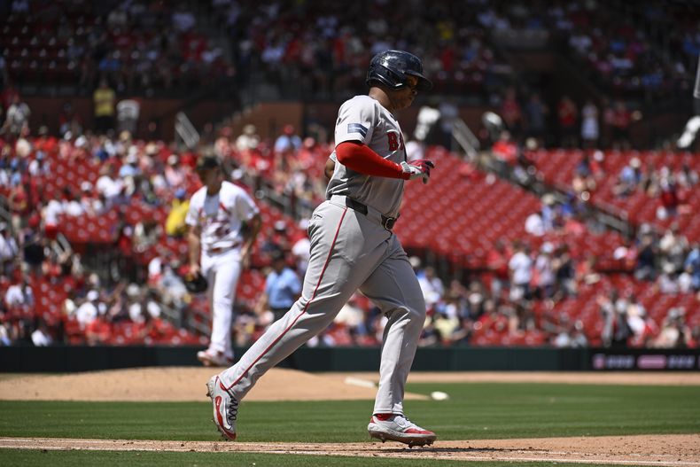 Rafael Devers, derecha, de los Medias Rojas de Boston, dobla después de primera después de batear jonrón de dos carrers, mientras el relevista de los Cardenales de San Luis, Ryan Fernández, detrás de él, espera durante la sexta entrada del juego de béisbol del domingo 19 de mayo de 2024, en San Luis. (AP Foto/Joe Puetz)