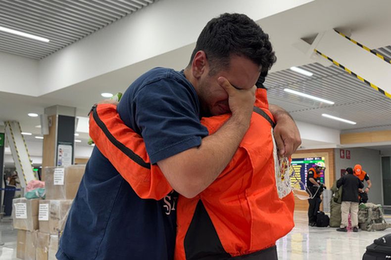 German Bello, derecha, voluntario de la brigada mexicana de búsqueda y rescate Topos Azteca, abraza a un venezolano que se acercó al equipo para agradecerles mientras salían para Venezuela desde el Aeropuerto de Ciudad de México, el martes 30 de junio de 2026. (AP Foto/Fernanda Pesce)