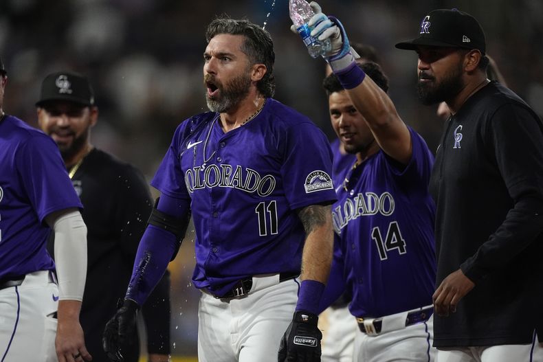 Jake Cave (11), de los Rockies de Colorado, es felicitado por sus compañeros de equipo después de dejar tendidos a los Cerveceros de Milwaukee con un sencillo productor de la carrera del triunfo ante el relevista Joel Payamps en la 10ma entrada del juego de béisbol del lunes 1 de julio de 2024, en Denver. (AP Foto/David Zalubowski)