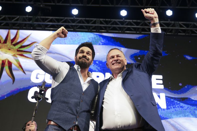 Álvaro Delgado, candidato presidencial del oficialista Partido Nacional, a la derecha, y Andrés Ojeda, aspirante presidencial del Partido Colorado, saludan a simpatizantes en las elecciones generales en Montevideo, Uruguay, el domingo 27 de octubre de 2024. (AP Foto/Matilde Campodónico)