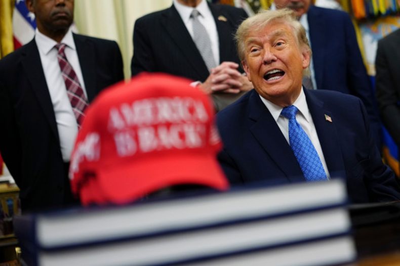 El presidente estadounidense Donald Trump habla junto a una gorra roja que dice, en inglés, “¡Estados Unidos está de regreso!”, en el Despacho Oval de la Casa Blanca, el viernes 26 de junio de 2026, en Washington. (AP Foto/Julia Demaree Nikhinson)