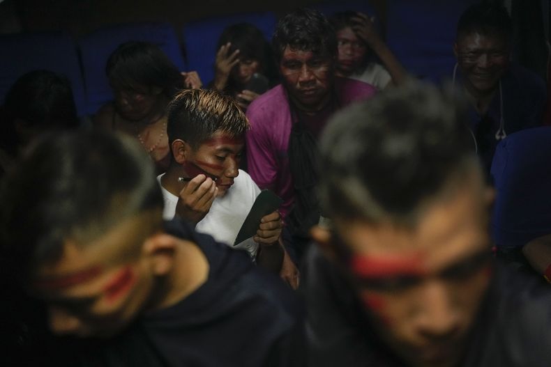 Un joven de la etnia yanomami se pinta el rostro mientras viaja en autobús para acudir a un evento indígena en la capital Brasilia, el martes 25 de abril de 2023, en Boa Vista, estado Roraima, Brasil. (AP Foto/Matías Delacroix)