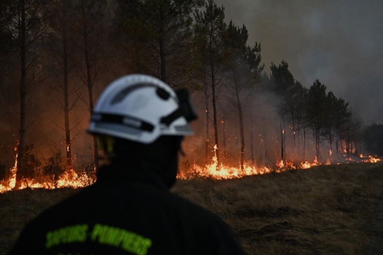 ARCHIVO - Un bombero camina frente a árboles en llamas mientras un incendio avanza cerca de Marcheprime, a las afueras de Burdeos, Francia, el 26 de julio de 2026. (AP Foto/Emma Da Silva, archivo)