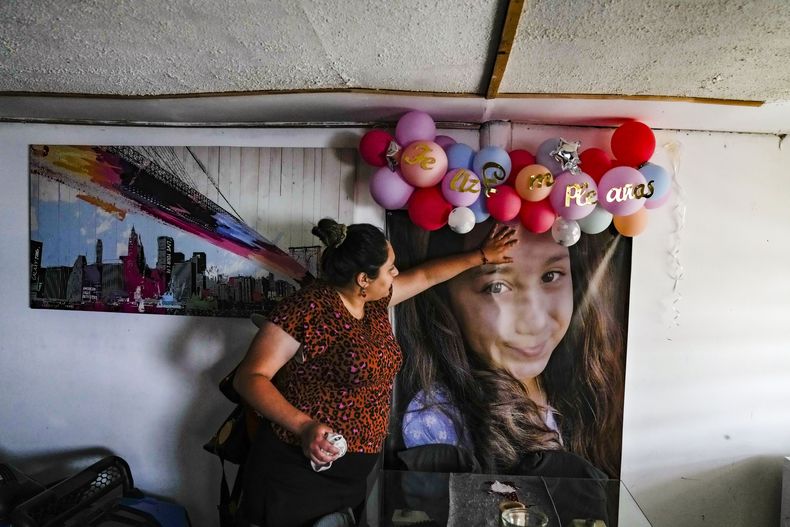 Camila Godoy, madre de Agustina Chacón, toca la foto de su hija fallecida colgada en la sala de la casa el día en que cumpliría 11 años en San Antonio, Chile, el viernes 20 de diciembre de 2024. Agustina fue asesinada, cuando iba con su padre en el auto, por un hombre armado que erró su objetivo, en Santiago en enero. (AP Foto/Esteban Félix)