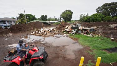 Un hombre se desplaza con su hijo cerca de una casa destruida el mes anterior al paso del huracán Lala, mientras las inundaciones del huracán Nolo retroceden, el domingo 27 de septiembre de 2026, en Naalehu, Hawai. (AP Foto/Gregory Bull)