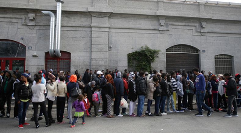 ARCHIVO – Un grupo de migrantes forma una fila para entrar a un comedor en Milán, Italia, el 21 de octubre de 2016. (AP Foto/Luca Bruno, Archivo)