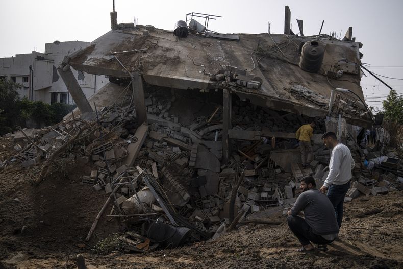 Palestinos inspeccionan los escombros de una vivienda alcanzada por un ataque aéreo israelí en Deir al-Balah, en el centro de la Franja de Gaza, el 12 de mayo de 2023. (AP Foto/Fatima Shbair)
