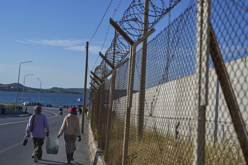 Un par de refugiados caminan junto a una cerca con alambre de púas afuera del campamento de refugiados y migrantes de Kara Tepe, el 13 de mayo de 2025, en la isla de Lesbos, Grecia. (AP Foto/Petros Giannakouris)