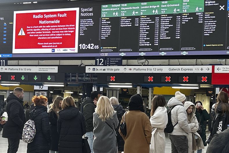 Viajeros observan los tableros de información en la Estación Victoria en Londres, el viernes 6 de diciembre de 2024, luego que problemas con un sistema de radio utilizado por los conductores y señalizadores en todo el país provocaran una interrupción masiva del servicio durante el concurrido trayecto matinal. (AP Foto/Kirsty Wigglesworth)