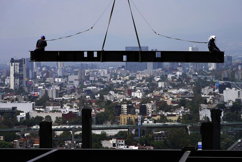 ARCHIVO - Trabajadores de la construcción sentados en una viga que cuelga de una grúa en una construcción de edificios residenciales de altura, en Ciudad de México, en junio de 2022. El presidente de México dijo el viernes 1 de diciembre de 2023 que el salario mínimo tendrá un aumento del 20% en 2024. (AP Foto/Marco Ugarte, Archivo)