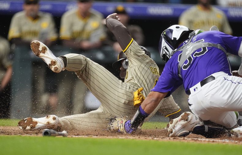 Luis Campusano, de los Padres de San Diego, izquierda, se barre en el plato para anotar con un doble del emergente Tyler Wade mientras el receptor de los Rockies de Colorado, Elías Díaz, derecha, lo toca de forma tardía en la octava entrada de un juego de béisbol el lunes 22 de abril de 2024, en Denver. (Foto AP/David Zalubowski)