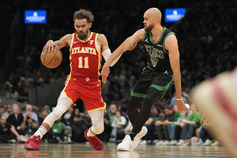 Trae Young, de los Hawks de Atlanta, hace una maniobra para eludir a Derrick White, de los Celtics de Boston, en el encuentro del sábado 18 de enero de 2025 (AP Foto/Robert F. Bukaty)