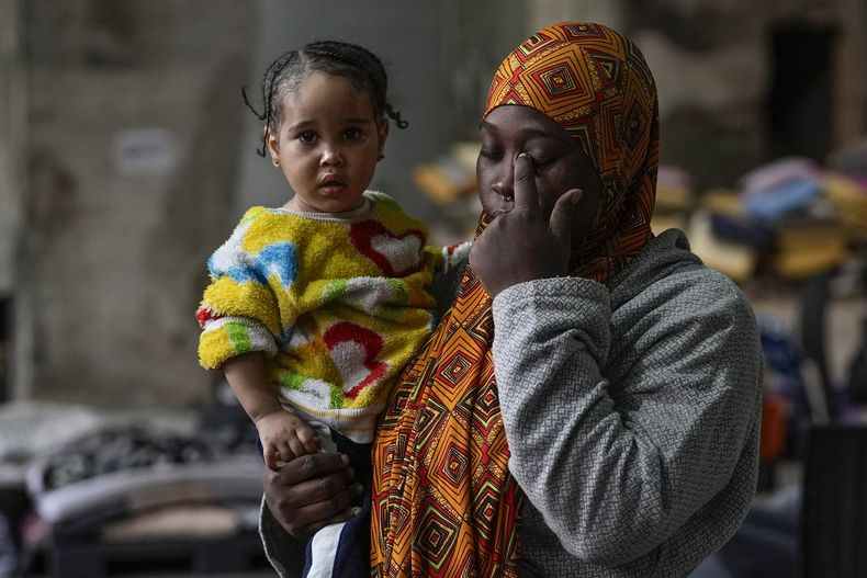 La trabajadora migrante de Sierra Leona Isatta Bah, de 24 años, reacciona mientras sostiene a su hija, Blessing, de un año, durante una entrevista con The Associated Press mientras espera a ser repatriada a casa, en un concesionario de autos convertido en refugio en Hazmieh, al este de Beirut, Líbano, el miércoles 4 de diciembre de 2024. (AP Foto/Hassan Ammar)