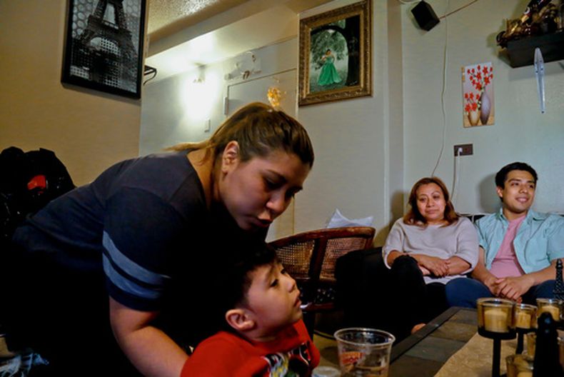 Rosa, segunda de la derecha, que pidió no revelar su apellido, una inmigrante indocumentada que recibía asistencia pero dejó de recibirla por temor a la deportación, con su hijo Edgar, a la extrema derecha y su nieto Logan, en su hogar en Nueva York, el 17 de mayo del 2017. (AP foto/Bebeto Matthews)