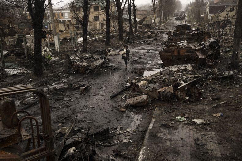 Una mujer camina entre tanques rusos destruidos en Bucha, en las afueras de Kiev, Ucrania, el domingo 3 de abril de 2022. (AP Foto/ Rodrigo Abd)