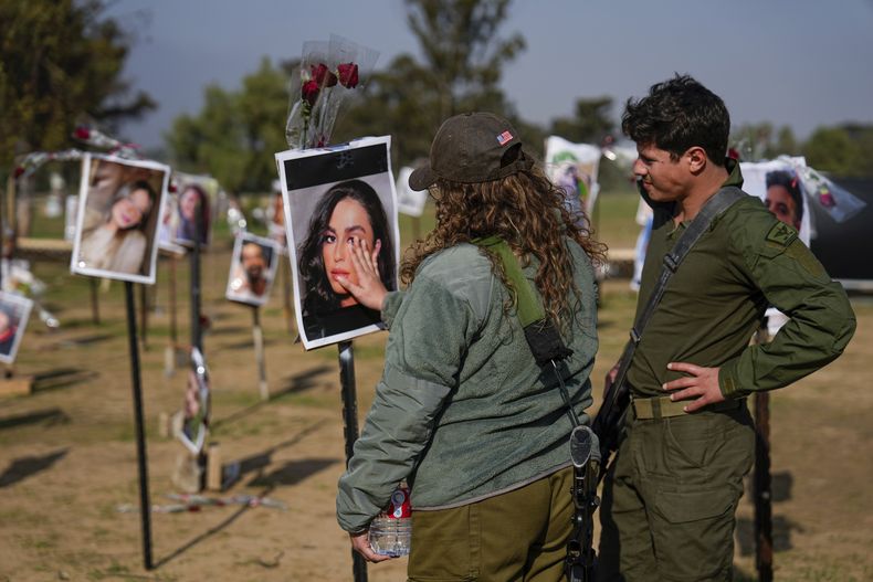 Soldados israelíes miran fotos de personas muertas o en cautiverio de Hamás durante el ataque de los milicianos al festival musical Nova en el sur de Israel, exhibidas en el lugar del hecho para conmemorar la masacre del 7 de octubre, cerca del kibbutz Reim, viernes 1 de diciembre de 2023. (AP Foto/Ariel Schalit)
