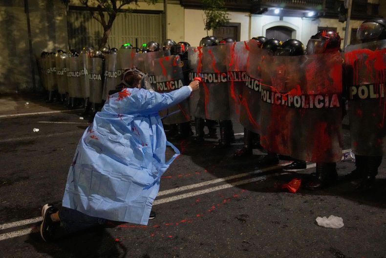 Un manifestante antigubernamental rocía a la policía con pintura roja cerca del Congreso durante una protesta contra el presidente interino José Jerí, el miércoles 15 de octubre de 2025, en Lima, Perú. (AP Foto/Martín Mejía)