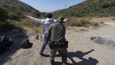 Un agente de la Oficina de Aduanas y Protección Fronteriza de Estados Unidos registra a un inmigrante que desea obtener asilo antes de que el hombre sea trasladado y procesado, el miércoles 5 de junio de 2024, cerca de Dulzura, California. (AP Foto/Gregory Bull).