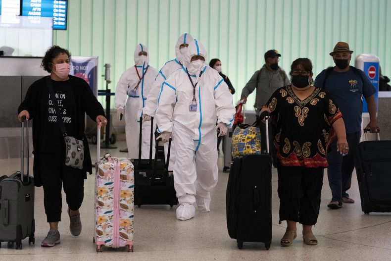 ARCHIVO - Miembros de la tripulación de vuelo de Air China con trajes para materiales peligrosos caminan por la zona de llegadas del Aeropuerto Internacional de Los Ángeles en Los Ángeles, el martes 30 de noviembre de 2021. (AP Foto/Jae C. Hong, Archivo)