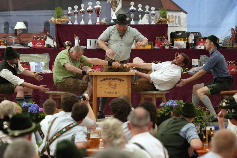 Dos hombres vestidos con ropa tradicional intentan jalar al rival por encima de la mesa en el Campeonato Alemán de Lucha de Dedos, el domingo 27 de abril de 2025, en Pang, cerca de Rosenheim, Alemania. (AP Foto/Matthias Schrader)