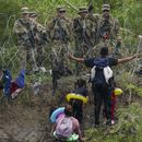 Un migrante abre los brazos frente a miembros de la Guardia Nacional de Texas ubicados detrás de alambre de púas en una de las márgenes del río Bravo, el jueves 11 de mayo de 2023, vistos desde Matamoros, México. (AP Foto/Fernando Llano)