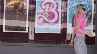 Una mujer pasa junto a carteles de las películas Oppenheimer, desde la izquierda, y Barbie, el jueves 20 de julio de 2023 en el Landmark Theatre de Los Ángeles. (Foto AP/Chris Pizzello)