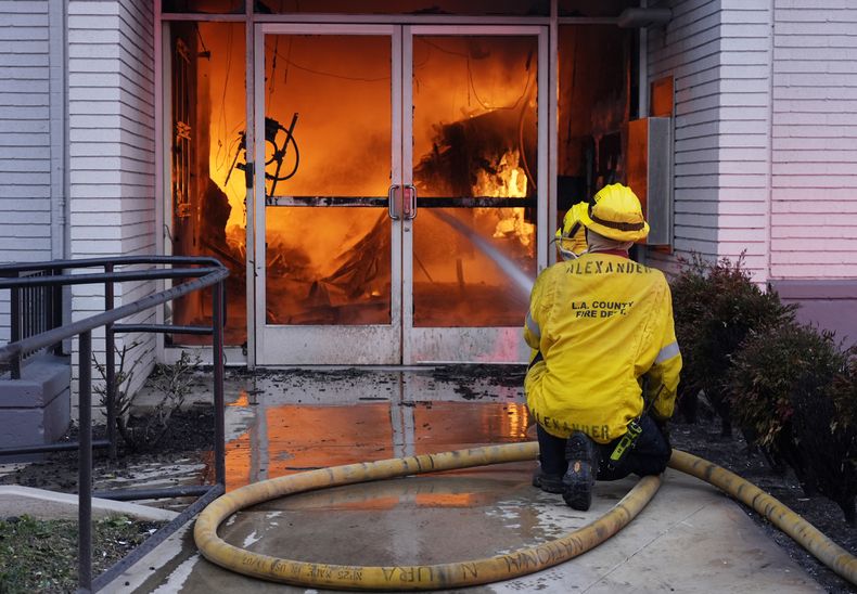 Bomberos combaten un incendio en la entrada de una sucursal de Bank of America envuelta en llamas en Lake Avenue, el miércoles 8 de enero de 2025, en la sección de Altadena, de Pasadena, California. (AP Foto/Chris Pizzello)