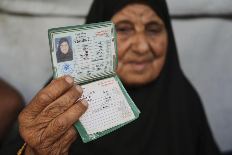 Ghalia Abu Moteir, cuya familia huyó de lo que hoy es Israel durante la guerra de 1948 que dio paso a la creación del Estado israelí, muestra sus documentos en una tienda de campaña en Jan Yunis, Franja de Gaza, después de ser desplazada de su hogar en Rafah, por la actual guerra, el miércoles 14 de mayo de 2025. (AP Foto/Abdel Kareem Hana)