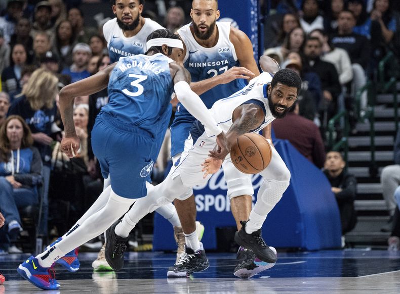 Kyrie Irving, derecha, de los Mavericks de Dallas, trata de robar el balón al alero de los Timberwolves de Minnesota, Jaden McDaniels (3), durante la segunda mitad del juego de baloncesto de la NBA, el domingo 7 de enero de 2024, en Dallas. (AP Foto/Jeffrey McWhorter)