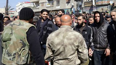 americateve | Rebeldes sirios, al fondo, conversan con fuerzas del gobierno sirio, en primer plano, tras de que las partes concertaran un acuerdo de reconciliaci&oacute;n en el poblado de Babila, al sureste de Damasco, Siria, el lunes 17 de febrero de 2014. El domingo