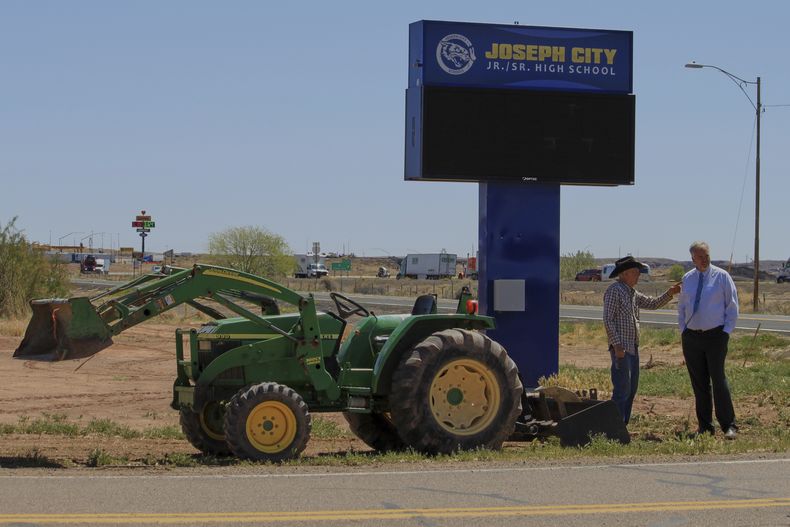 El ganadero Brantley Baird, izquierda, y el superintendente escolar de Joseph City, Bryan Fields, conversan sobre un marcador histórico cerca del letrero de la escuela secundaria en Joseph City, Arizona, el miércoles 23 de abril de 2025. (AP Foto/Susan Montoya Bryan)