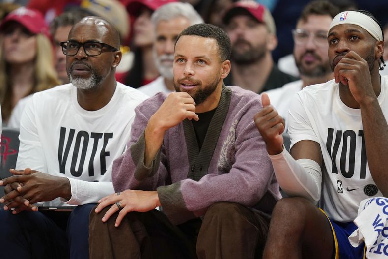 El escolta de los Warriors de Golden State, Stephen Curry, en el centro, observa desde el banquillo durante la primera mitad de un partido contra los Houston Rockets, el sábado 2 de noviembre de 2024, en Houston. (AP Foto/Eric Christian Smith)