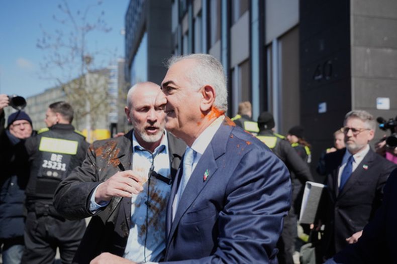 El iraní Reza Pahlavi, hijo exiliado del sha Reza Pahlavi, protegido por fuerzas de seguridad tras ser atacado con un líquido rojo después de una conferencia de prensa en Berlín, Alemania, el jueves 23 de abril de 2026. (AP Foto/Markus Schreiber)