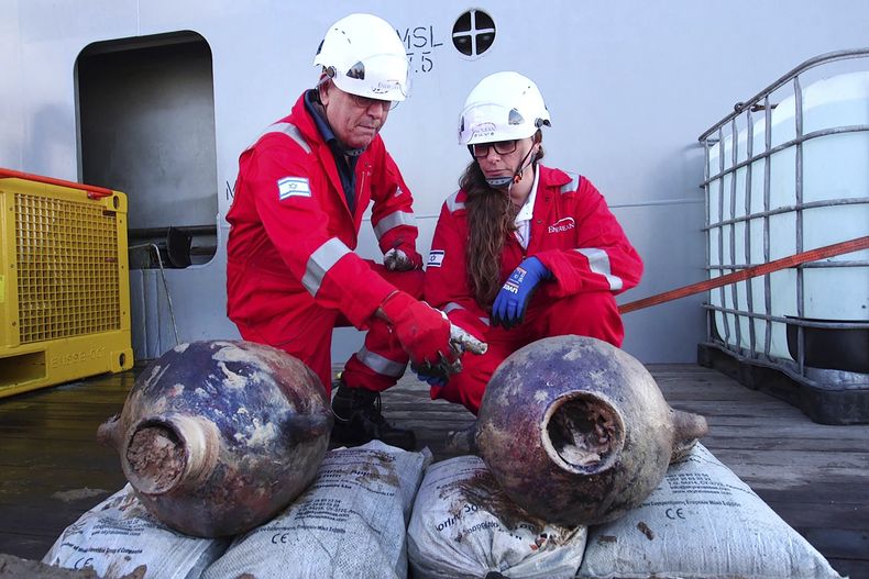 Jacob Sharvit (izq) y Karnit Bahartan (der) con jarrones antiguos sacados de un barco que descubrieron a unos 90 kilómetros de la costa israelí. Foto cortesía de la Autoridad de Antigüedades de Israel, entregada el 20 de junio del 2024 (Emil Aladjem/ Autoridad de Antigüedades de Israel via AP)