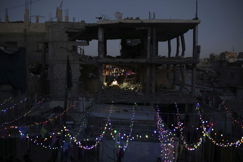 Palestinos colocan decoraciones cerca de sus viviendas destrozadas por la guerra, antes del inicio del mes sagrado del islam, el Ramadán, en Jan Yunis, en el sur de la Franja de Gaza, el 28 de febrero de 2025. (AP Foto/Jehad Alshrafi)