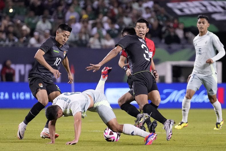Andrés Montaño (adelante, a la izquierda), de la selección de México, cae al disputar un balón con Yomar Rocha (3), de Bolivia, en un amistoso internacional disputado el viernes 31 de mayo de 2024 en Chicago (AP Foto/Charles Rex Arbogast)