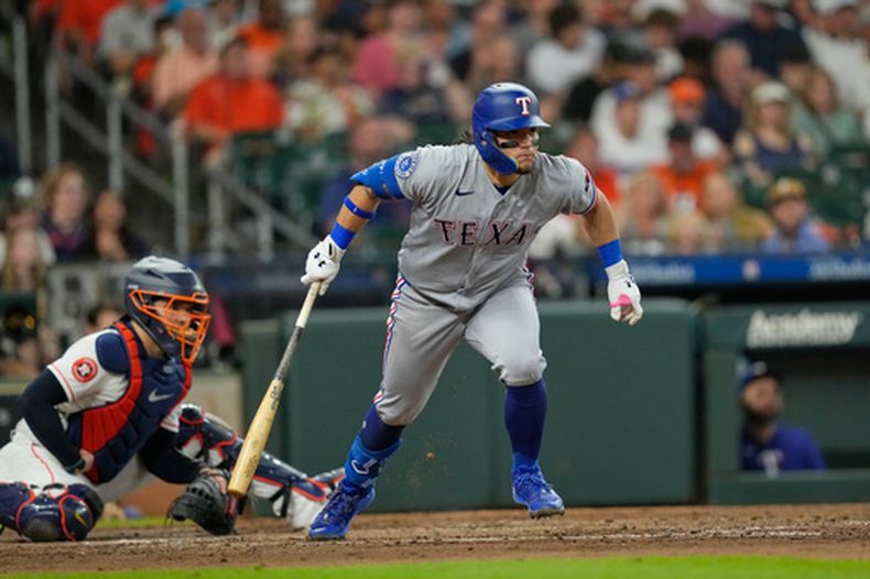 Alejandro Osuna, de los Rangers de Texas, a la derecha, observa su sencillo impulsor frente al receptor de los Astros de Houston, Yainer Díaz, durante la cuarta entrada de un partido de béisbol el sábado 1 de agosto de 2026, en Houston. (Foto AP/David J. Phillip)