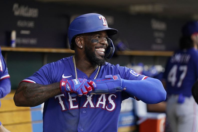 El cubano Adolis García, de los Rangers de Texas, sonríe en la cueva tras anotar con un jonrón de Josh Jung en el juego ante los Tigres de Detroit, el martes 30 de mayo de 2023 (AP Foto/Carlos Osorio)