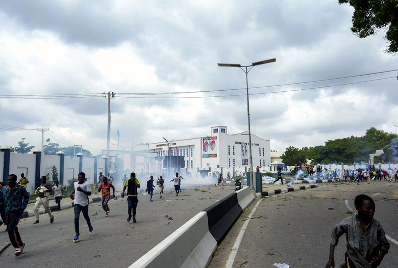 ARCHIVO - Personas huyen de los gases lacrimógenos durante una protesta callejera en Kano, Nigeria, el 1 de agosto de 2024. (Foto AP/Sani Maikatanga, Archivo)